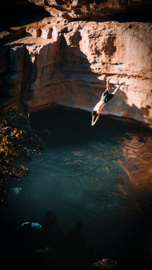 A person jumping into a pool from a cliff